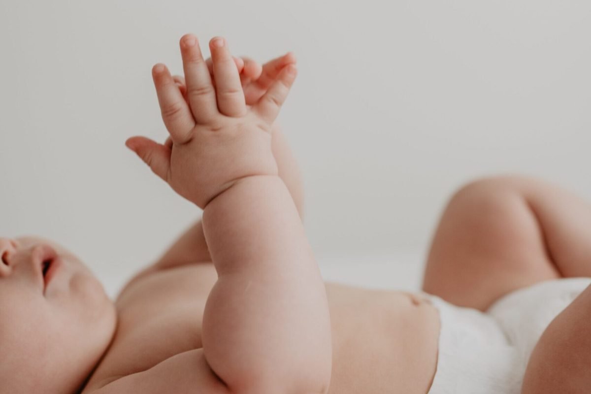 Close-up of a baby in a diaper reaching upward, showcasing innocence and new life.